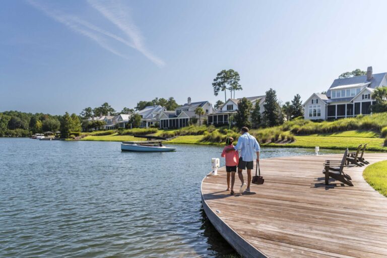 A couple walking on a dock next to the May River at Montage Palmetto Bluff